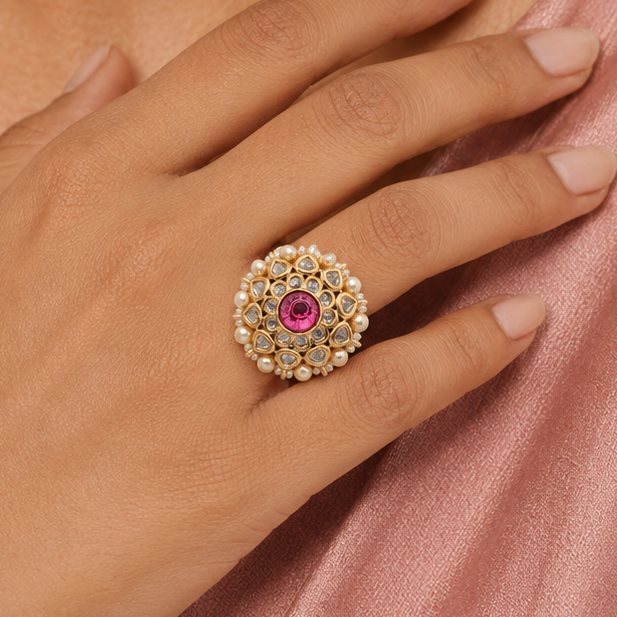 Gold-finish floral finger ring for women displayed on a neutral stone platform