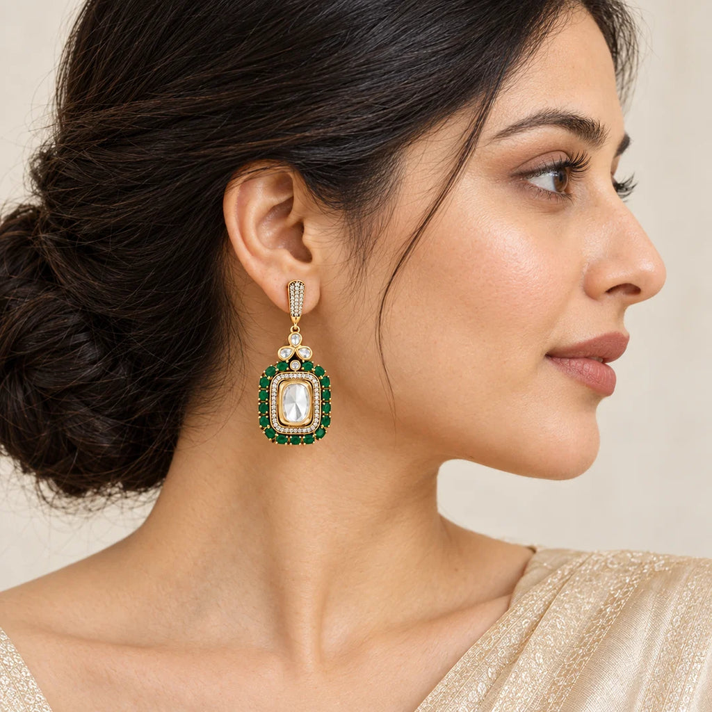 Side-profile Indian model wearing a Harita green rectangular drop earring with clear stones and gold-tone detailing.