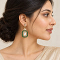 Side-profile Indian model wearing a Harita green rectangular drop earring with clear stones and gold-tone detailing.
