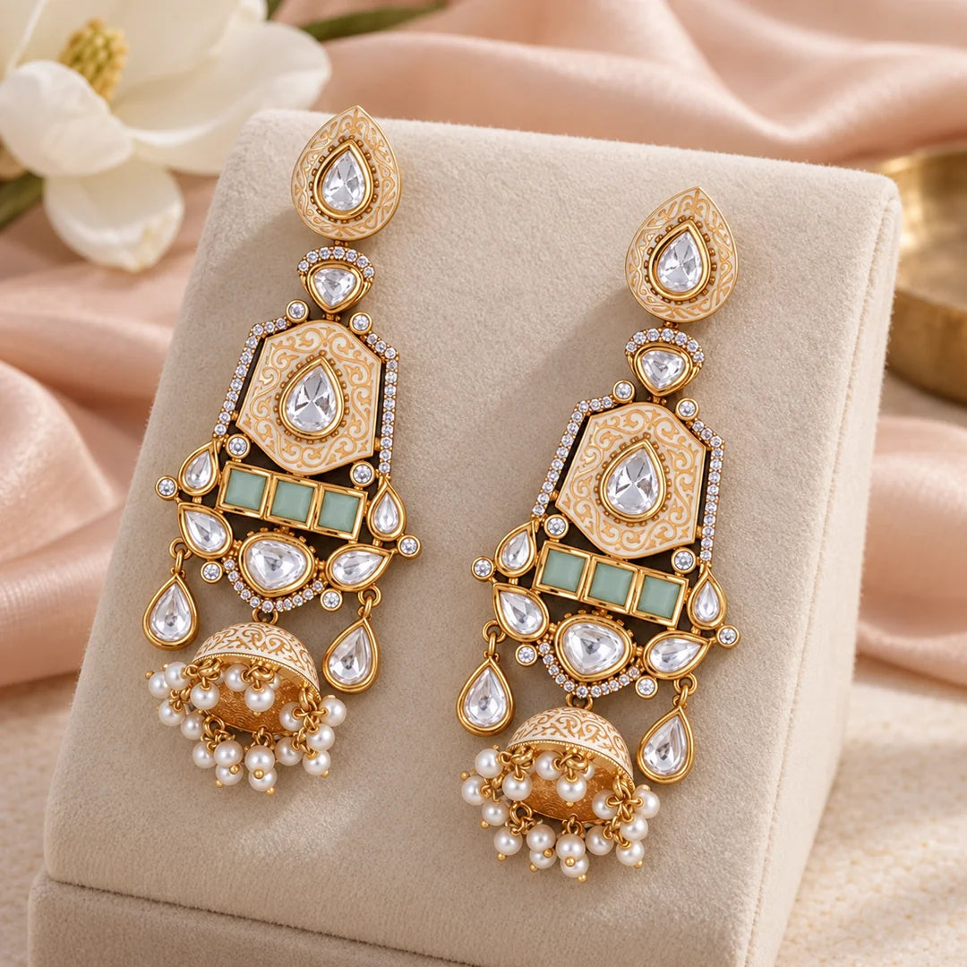 Ivory and mint long jhumka earrings hanging from a bronze display stand, showing teardrop tops and decorative bell-shaped drops.