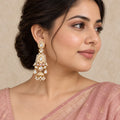 Indian model in a dusty rose saree wearing an ivory and pink long jhumka earring with clear stones and pearl-look fringe.