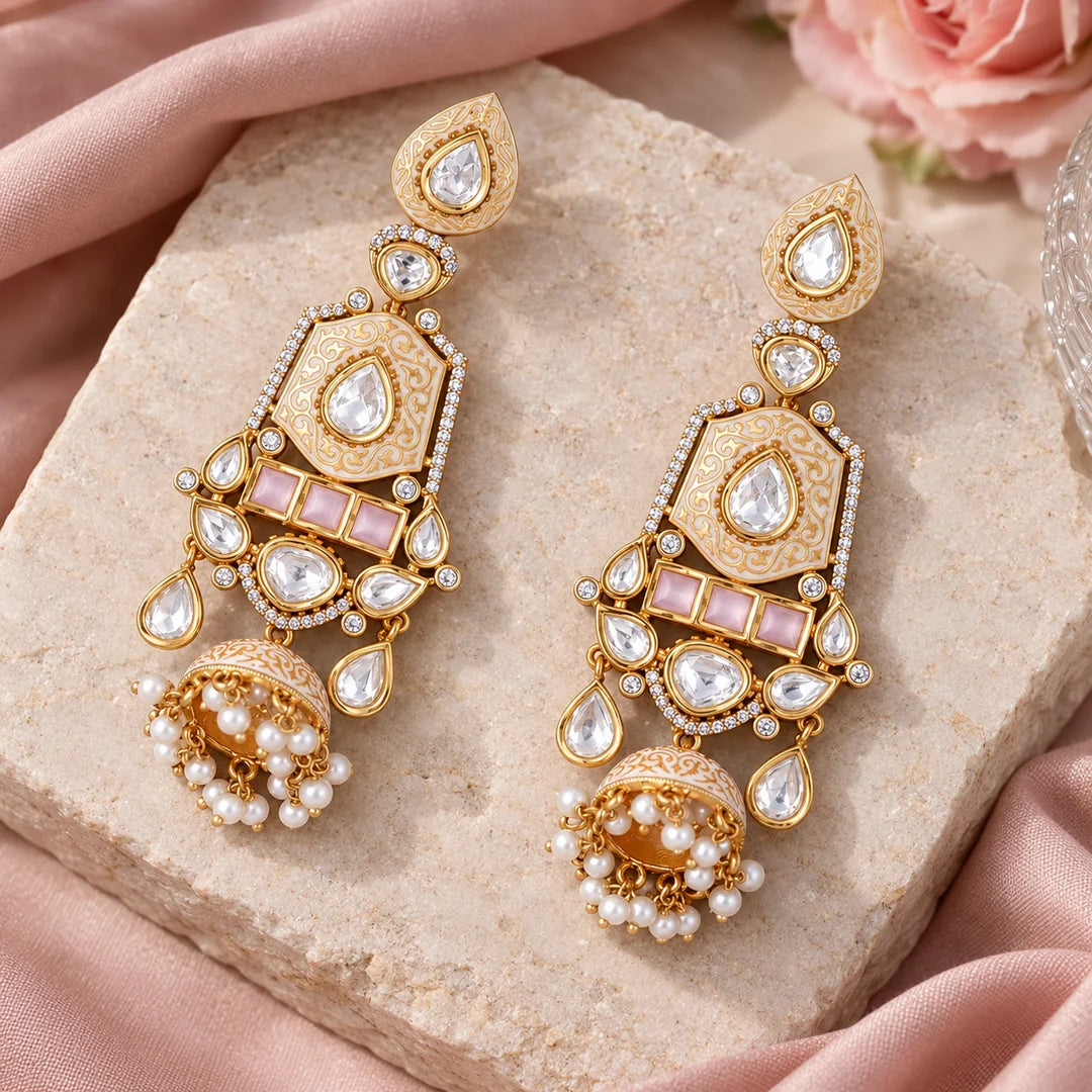 Pair of ivory and pink long jhumka earrings displayed on pale stone with blush silk and a pink rose.