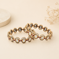 Ishani gold Kundan-style bangle pair displayed on a warm ivory luxury background