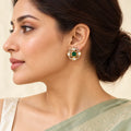 Side-profile model wearing Ishani green floral stud earrings with clear stones and gold-tone detailing.