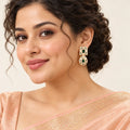 Indian model in a peach saree wearing a Kaashni ivory and green enamel-style drop earring, with her hair swept back.