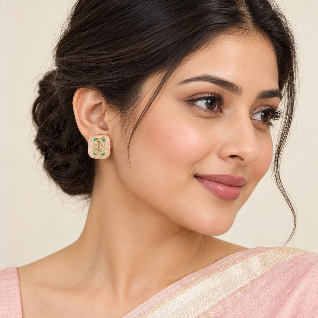 Indian model in a blush saree wearing a Kairavi rectangular stud with pink borders, turquoise-colour leaf motifs and a clear central stone.