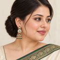 Indian model in an ivory saree with a forest-green border wearing a Kalika ivory and green floral jhumka with a pearl-style bead fringe.