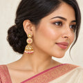 Indian model in an ivory saree with a rose border wearing a Kalika floral jhumka with an ivory and ruby-colour disc and cream bead fringe.