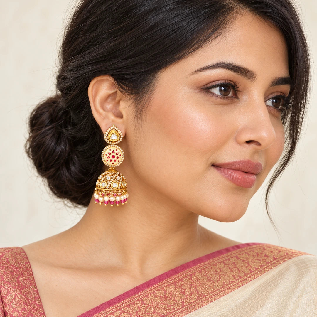 Indian model in an ivory saree with a rose border wearing a Kalika floral jhumka with an ivory and ruby-colour disc and cream bead fringe.