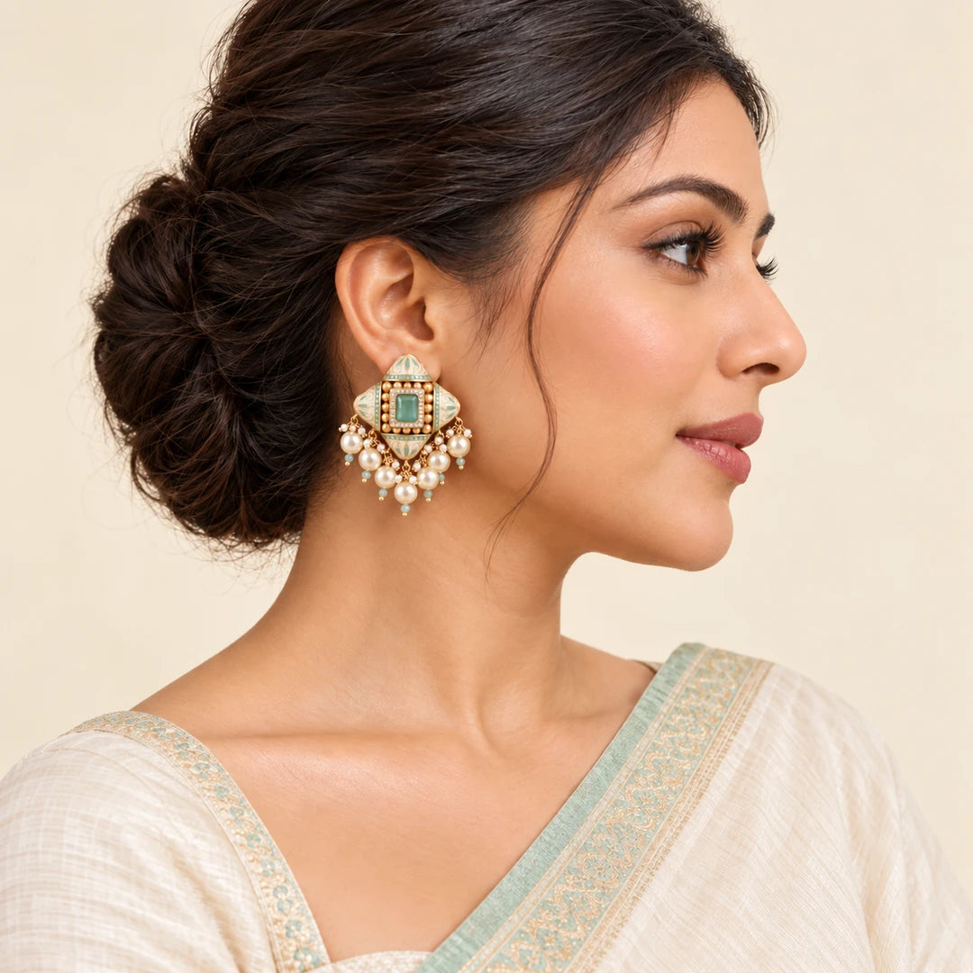 Indian model in an ivory saree with a mint border wearing a Kalindi ivory and mint earring with cream pearl-style drops.