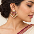 Close-up of an Indian model wearing a Kalindi ivory and ruby-colour earring with seven cream pearl-style drops and an ivory saree with a burgundy border.