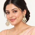 Indian model in a peach saree wearing Kalpita ivory and mint floral drop earrings with cream pearl-style fringe.