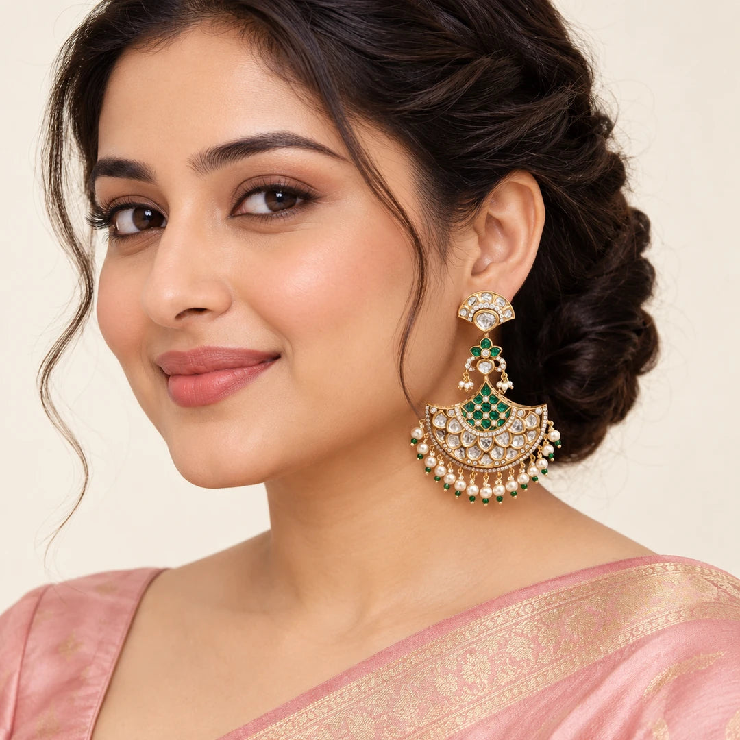 Model in a blush pink saree wearing a Kalyani green chandbali earring with clear stones and a cream pearl-style fringe.