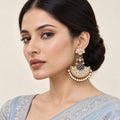 Model in a powder-blue embroidered saree wearing a Kalyani navy-blue chandbali earring with clear stones and cream pearl-style fringe.