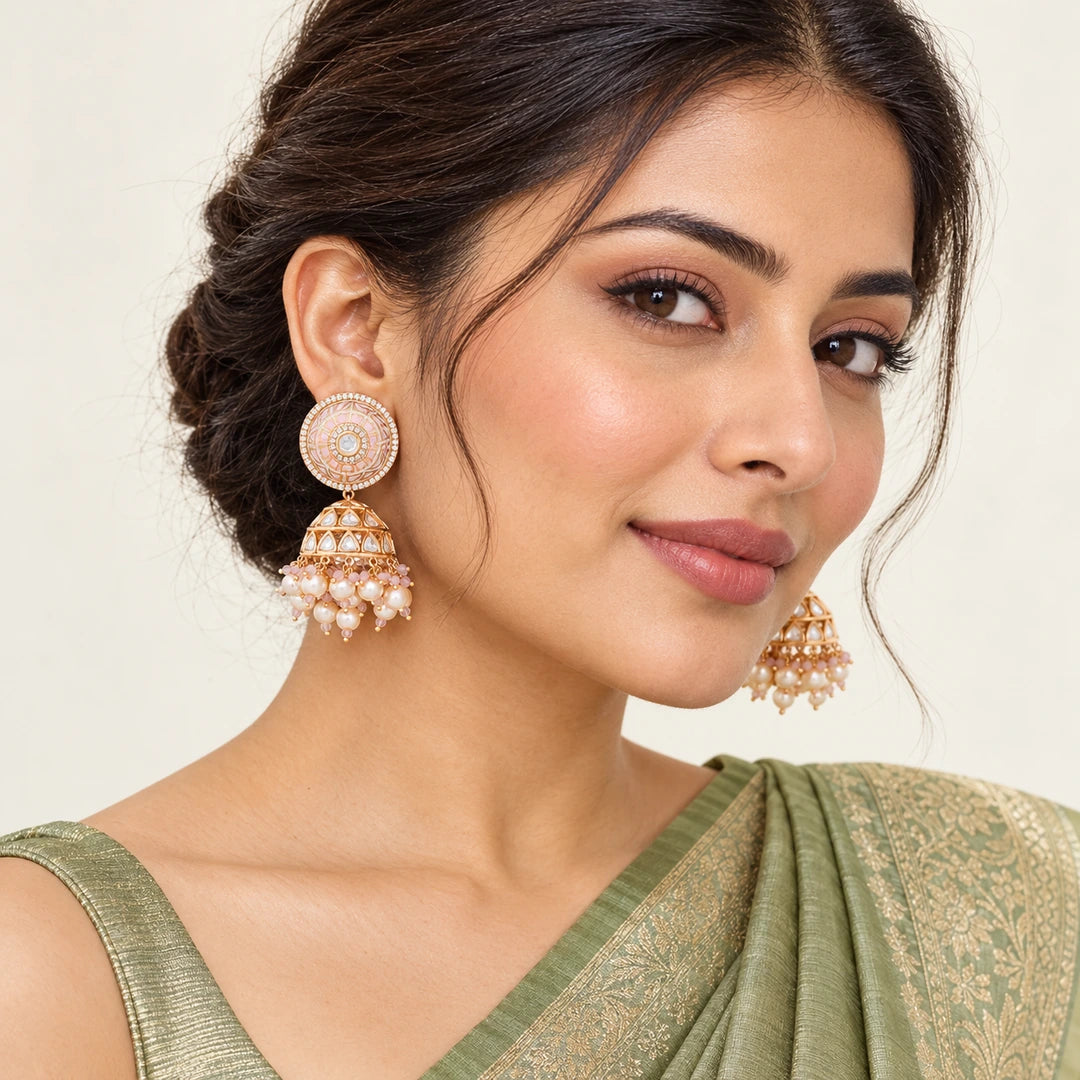 Model in a sage-green silk saree wearing Kamala ivory and blush jhumka earrings with clear stones and cream pearl-style fringe.