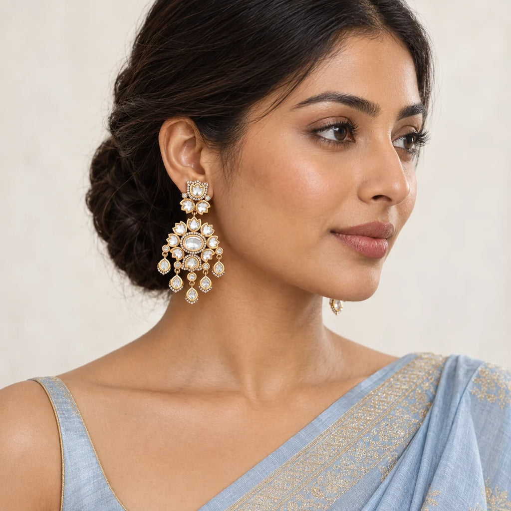 Indian model in a powder-blue saree wearing clear stone floral chandelier earrings with gold-tone settings and teardrop dangles.