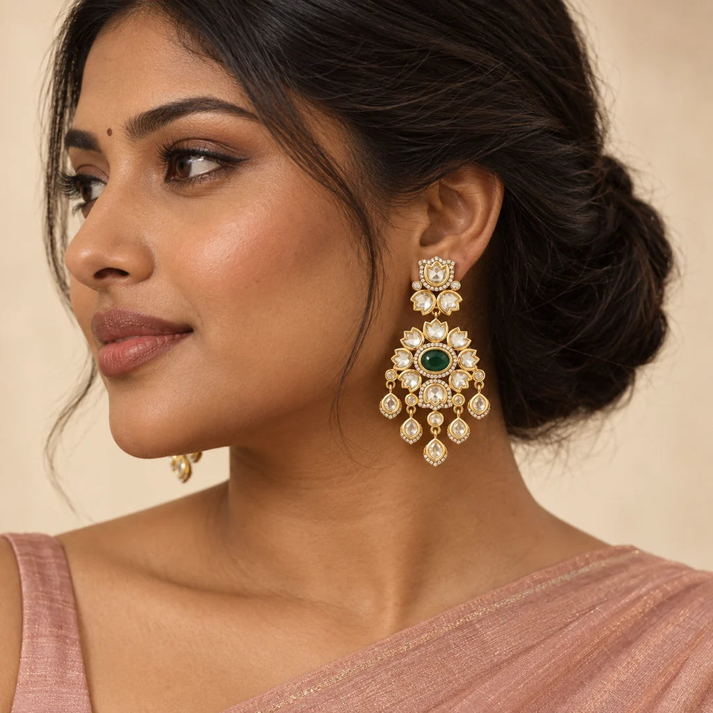 Indian model in a blush saree wearing a green floral chandelier earring with clear lotus-shaped stones and five teardrop dangles.