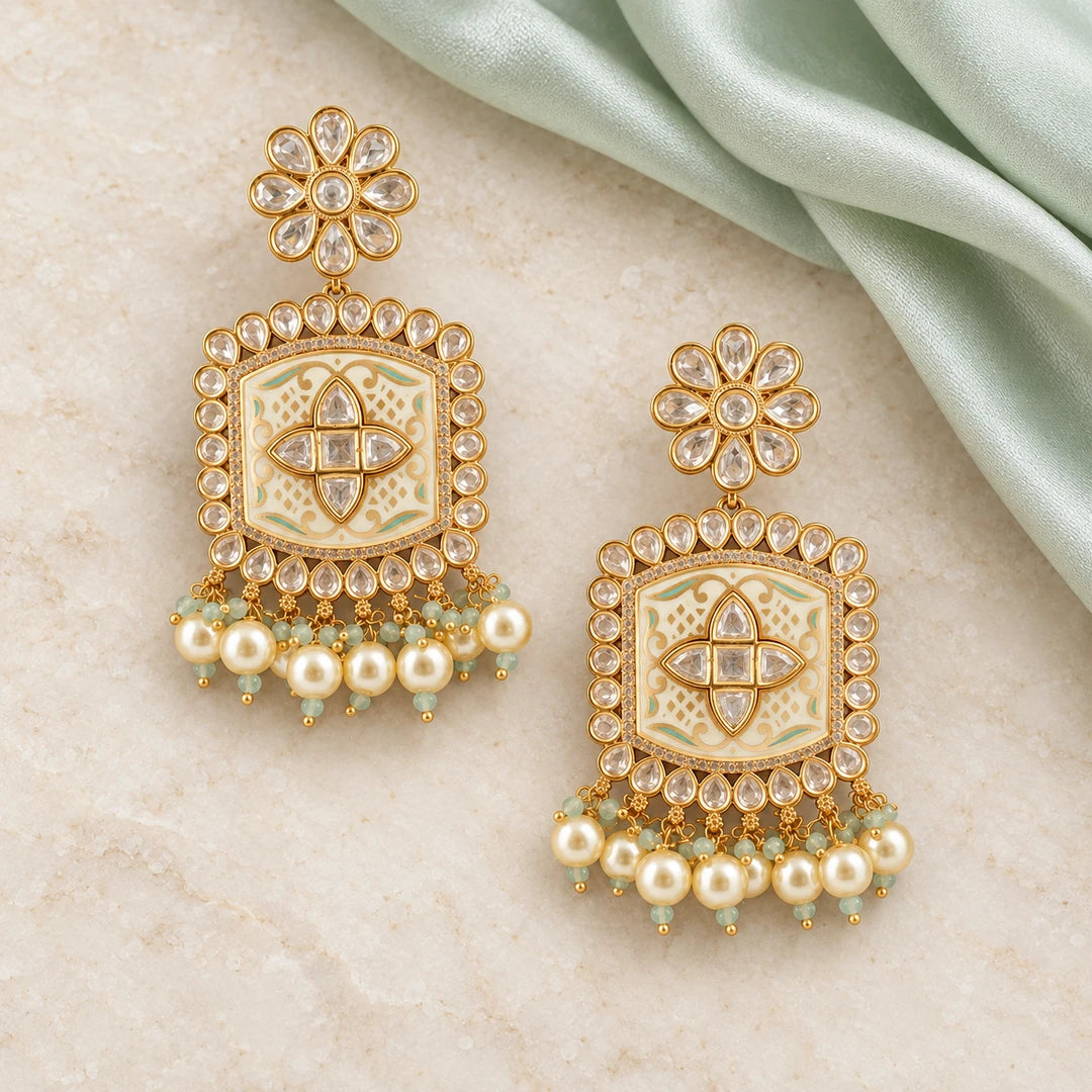 Pair of Kamini ivory and mint pearl-style drop earrings on cream stone beside mint silk, showing floral tops and gold-tone patterned panels.