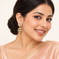 Indian model in a peach saree wearing a Kanavi ivory and green jhumka earring with clear floral detailing and pearl-style drops.