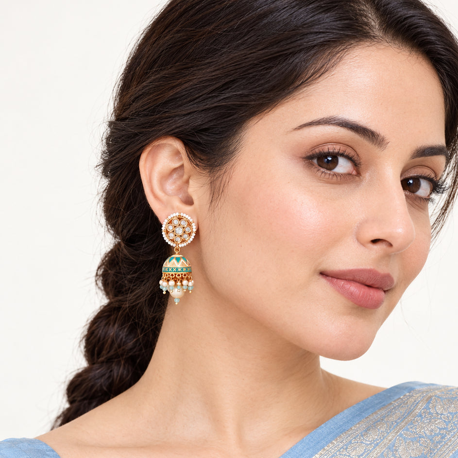 Indian model in a powder blue saree wearing a Kanavi ivory and turquoise jhumka earring with clear floral detailing and pearl-style drops.