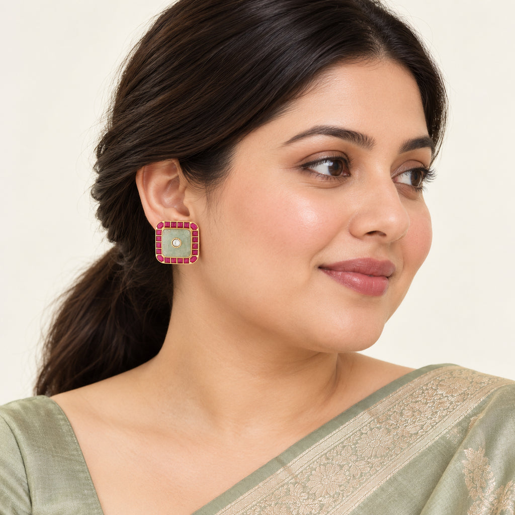 Indian model in a sage saree wearing a Kashika square stud earring with a pale green centre and ruby-colour border.
