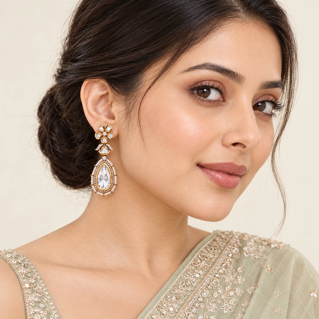 Model in a pale sage embroidered saree wearing a Kashmira clear floral teardrop earring with a cream pearl-style bead border.