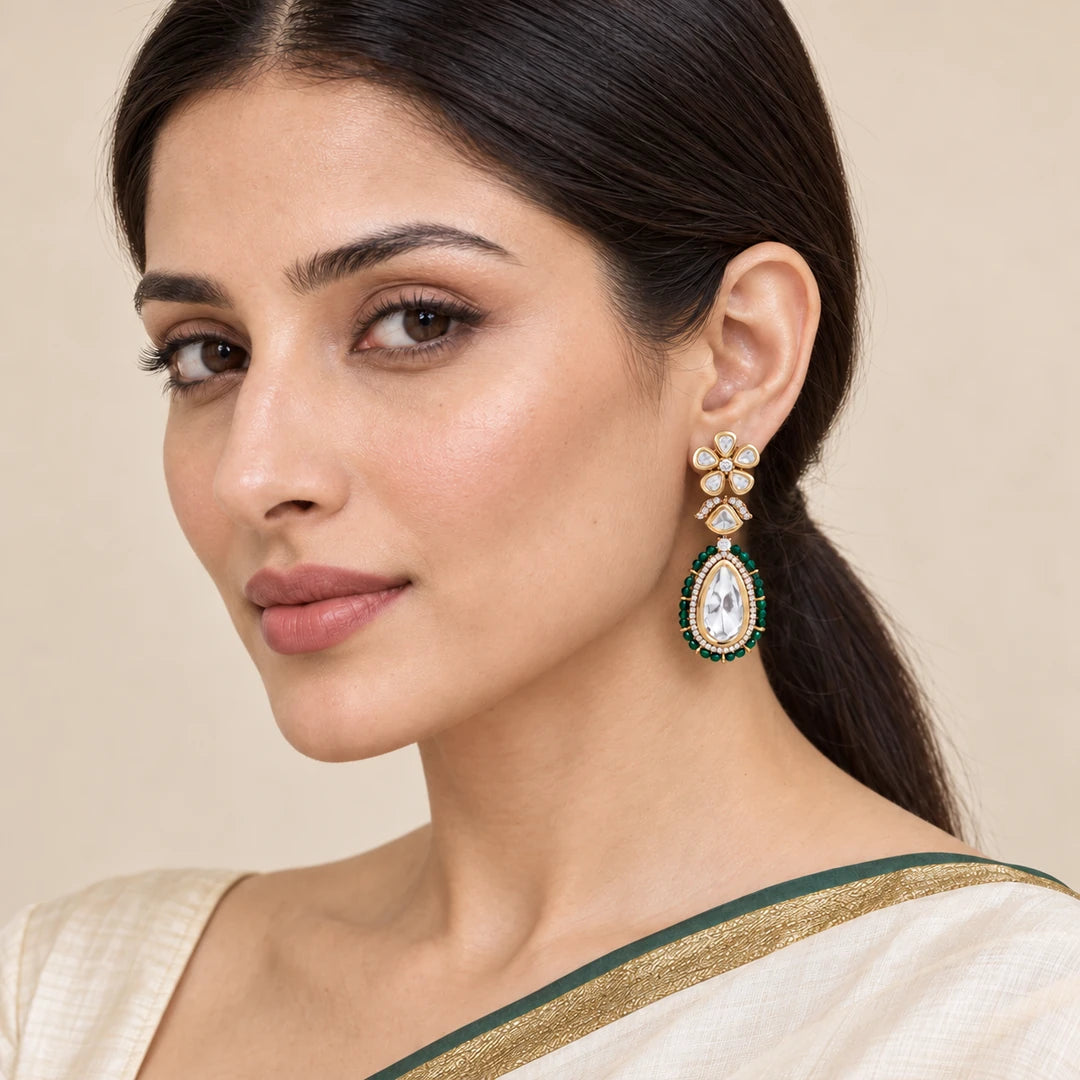 Model in an ivory saree with a green and gold border wearing a Kashmira green floral teardrop earring.