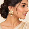 model wearing Kaushiki gold-tone floral drop earrings with oval clear centres, pear-shaped accents and teardrop pendants on a dark background.