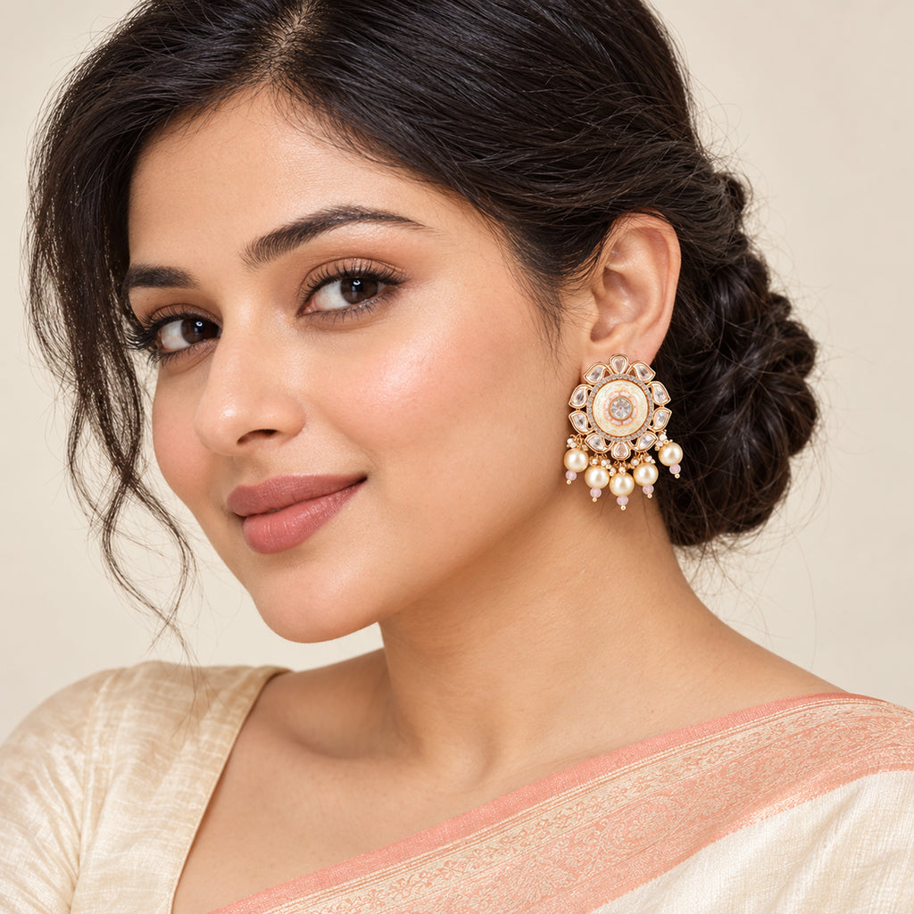 Indian model in an ivory saree with a peach border wearing a Kavini ivory and blush earring with clear floral detailing and five pearl-style drops.