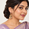 Model in a lavender silk saree wearing a Kavitha clear-stone hook jhumka with an antique-look gold-tone dome and cream pearl-style fringe.