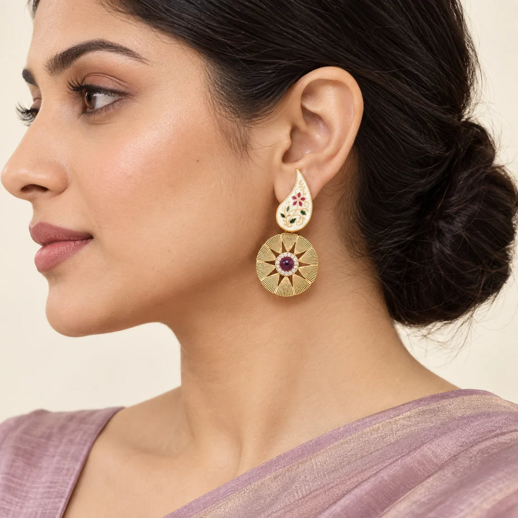 Model in side profile wearing a Kavya ivory paisley earring with a textured gold-tone disc and ruby-colour centre.