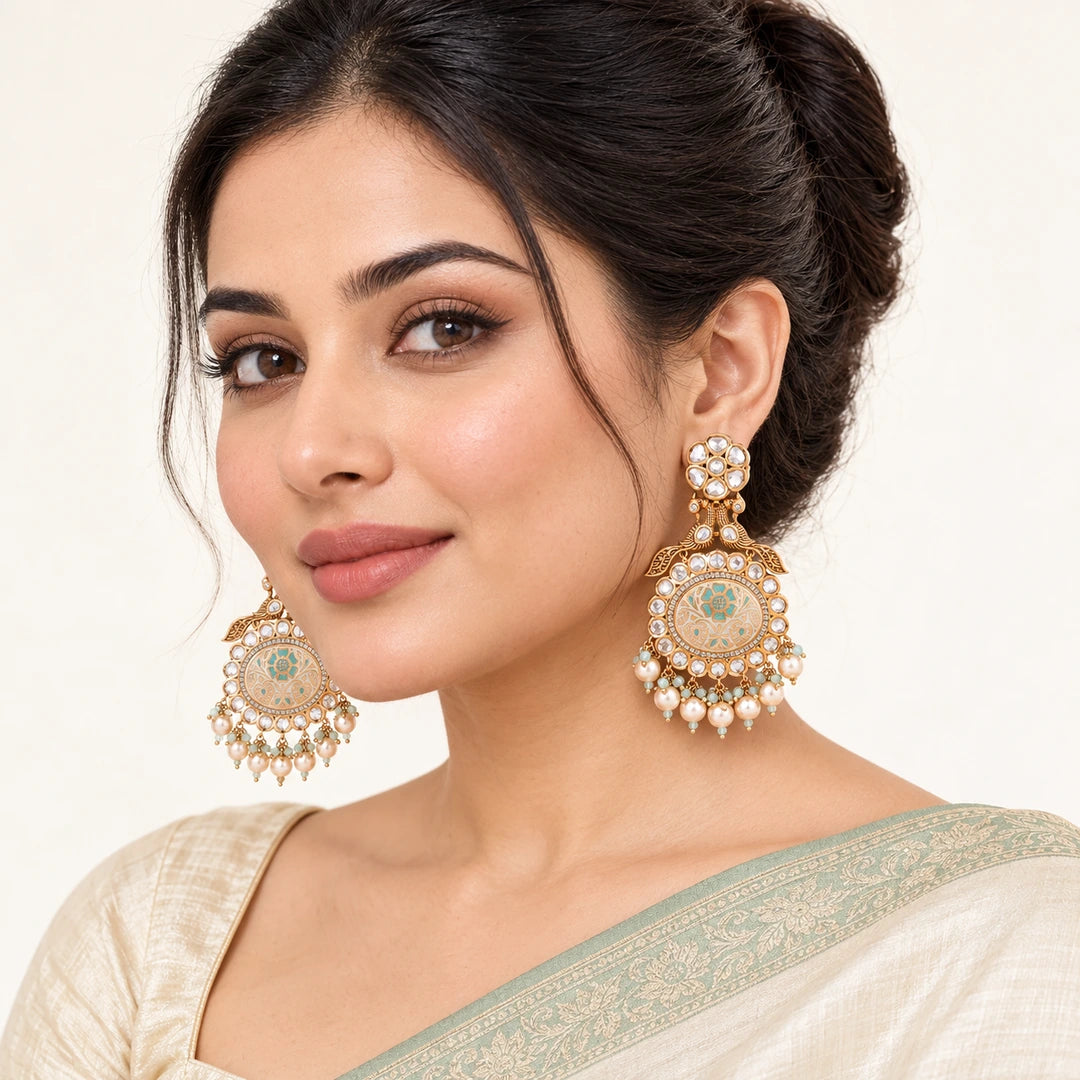 Model in an ivory saree with a sage border wearing Kesara ivory and mint peacock earrings with pearl-style drops.