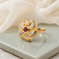 Gold-finish floral Kundan-look ring displayed on a soft neutral surface