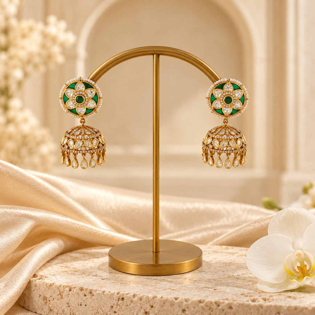 Pair of Kiranya green floral jhumka earrings with gold-tone stone-set domes and clear teardrop fringe against a cream stone background.