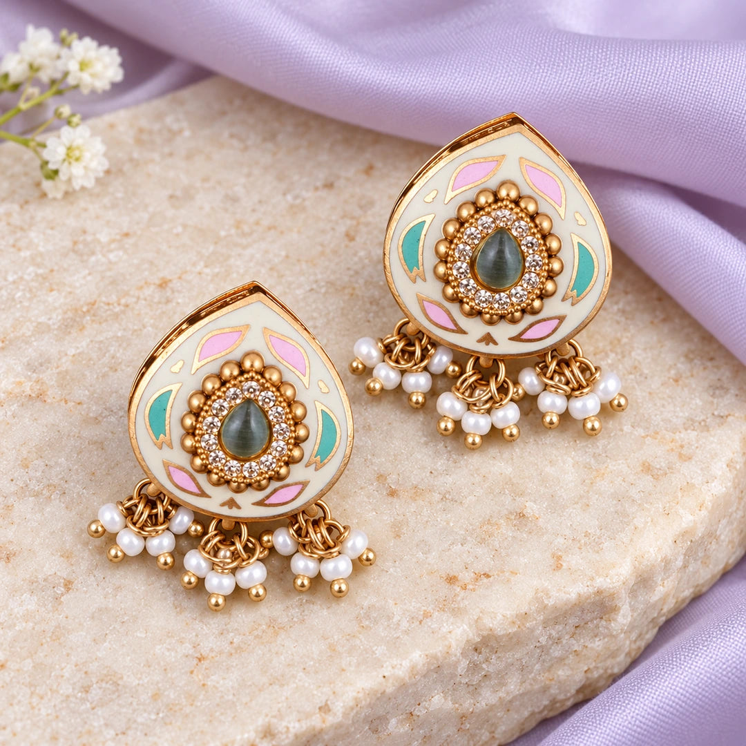 Pair of Kiyana ivory and pastel teardrop earrings on cream stone beside lavender silk and small white flowers.