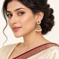 Indian model in an ivory saree with a burgundy border wearing a Kritika ruby-colour and pearl-style jhumka earring.