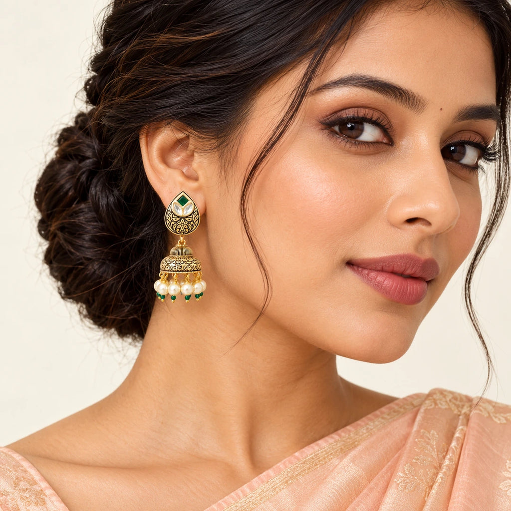 Model in a peach silk saree wearing Kritila green and pearl-style jhumka earrings with engraved gold-tone detailing.