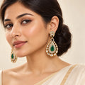 Indian model in an ivory saree wearing Kritvi green teardrop earrings with clear-stone borders and gold-tone detailing.