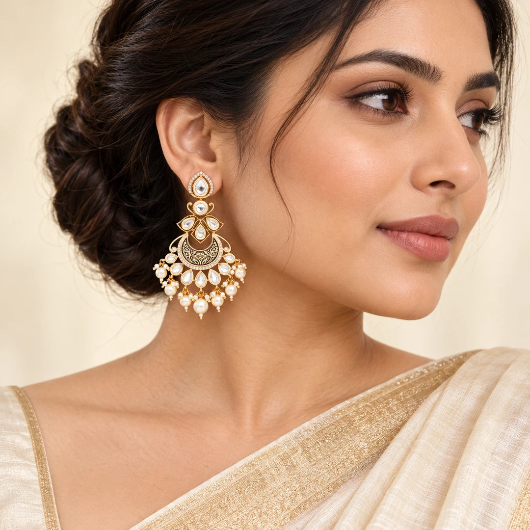 Indian model in an ivory and gold saree wearing a Kumudini chandbali earring with clear stones, an engraved crescent and cream pearl-style drops.