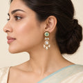 Side-profile model wearing a Malvika turquoise floral earring with clear teardrop stones and cream pearl-style beads.