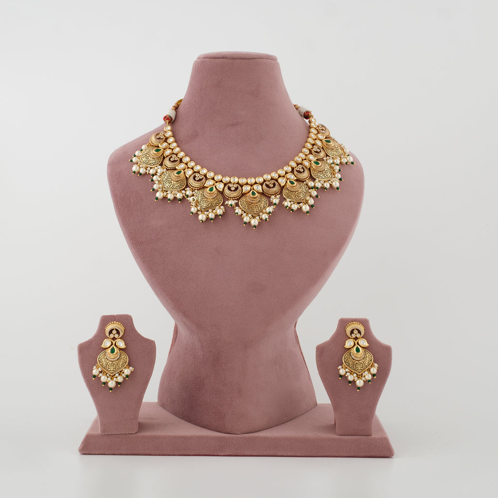 Mayurika antique gold-plated necklace set with green stones, white moti and matching earrings