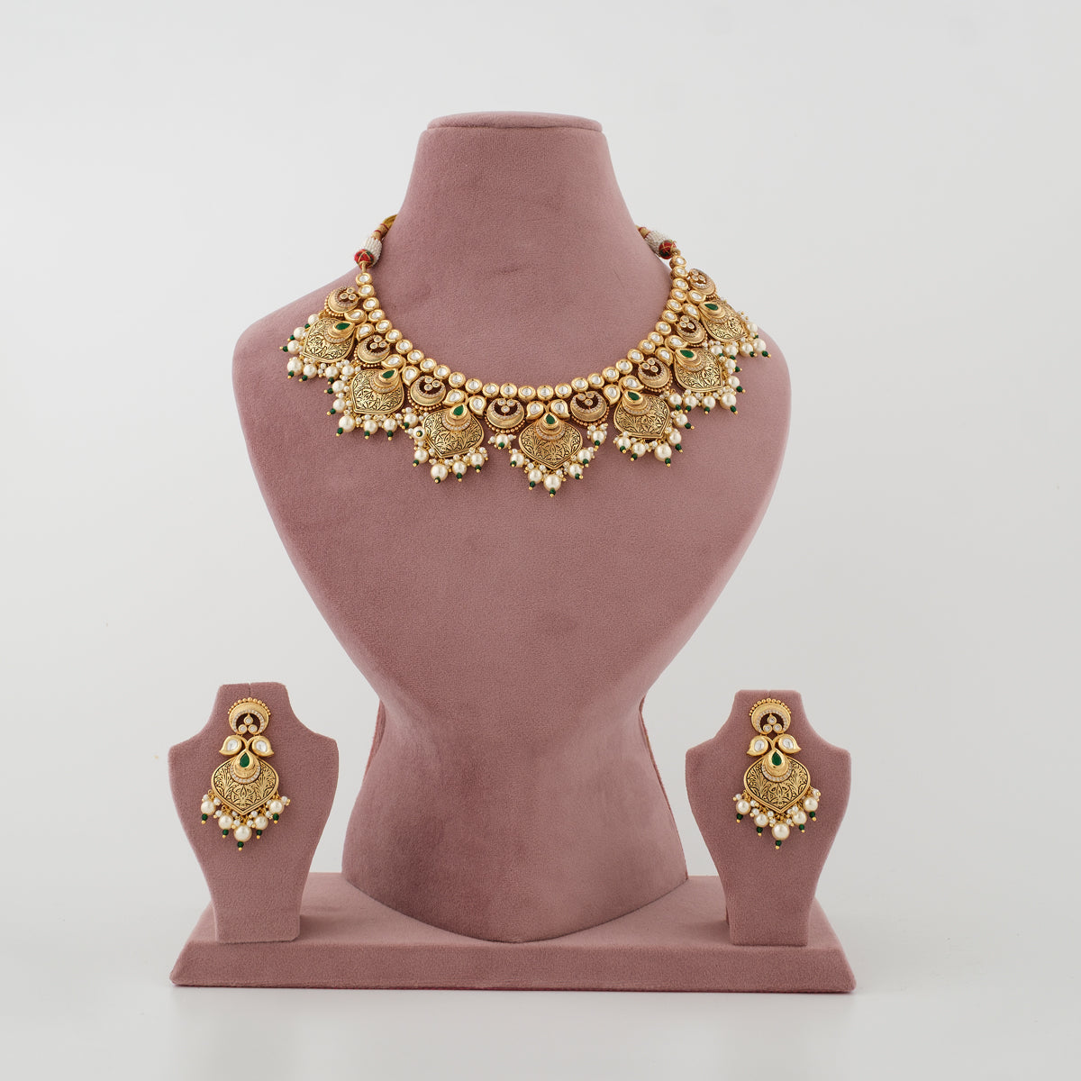 Mayurika antique gold-plated necklace set with green stones, white moti and matching earrings