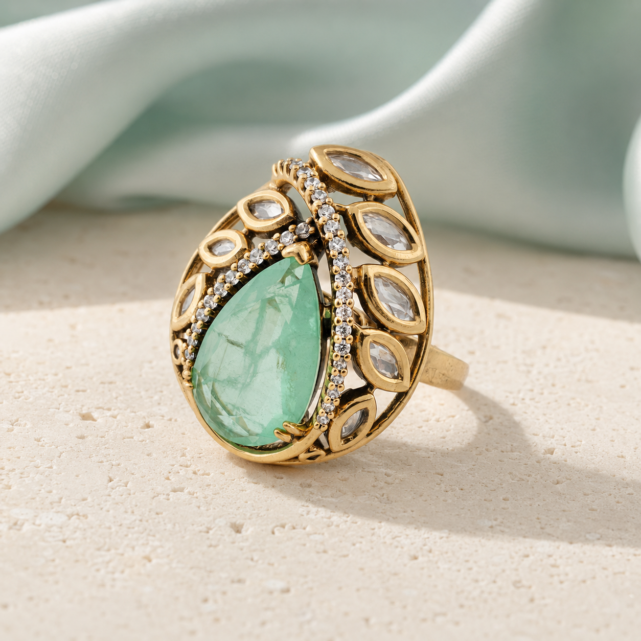 Mint-green teardrop statement ring displayed on a neutral luxury surface