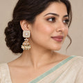 Model wearing ivory and mint jhumka earrings with floral square tops and pearl-look bead drops.