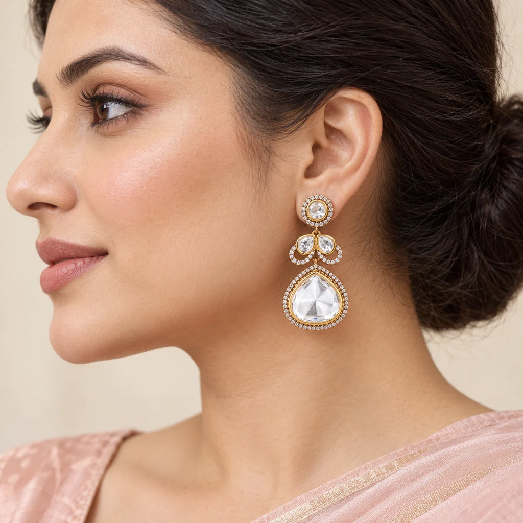 Side-profile Indian model in a blush saree wearing a Prisha clear stone teardrop earring with gold-tone detailing.