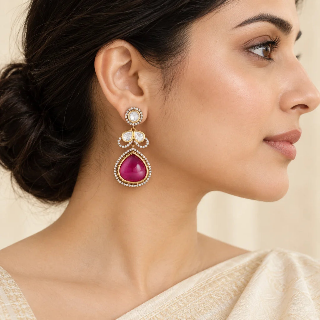 Side-profile Indian model in an ivory saree wearing a Prisha ruby-colour teardrop earring with clear stones.
