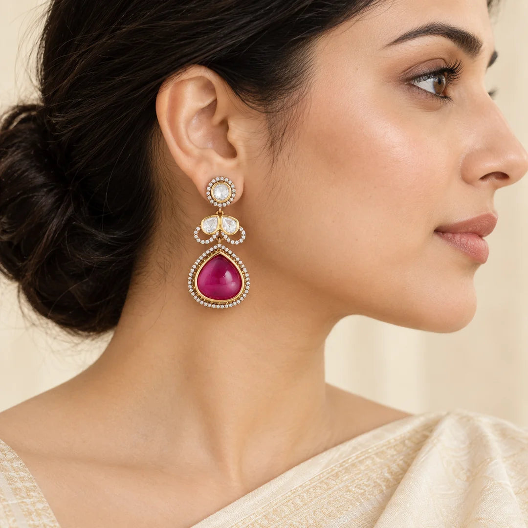 Side-profile Indian model in an ivory saree wearing a Prisha ruby-colour teardrop earring with clear stones.