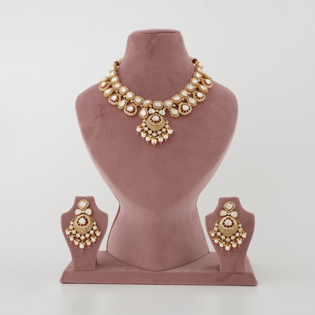 Gold-toned traditional jewelry set displayed on a dusty rose velvet mannequin bust, including a statement necklace and matching earrings.
