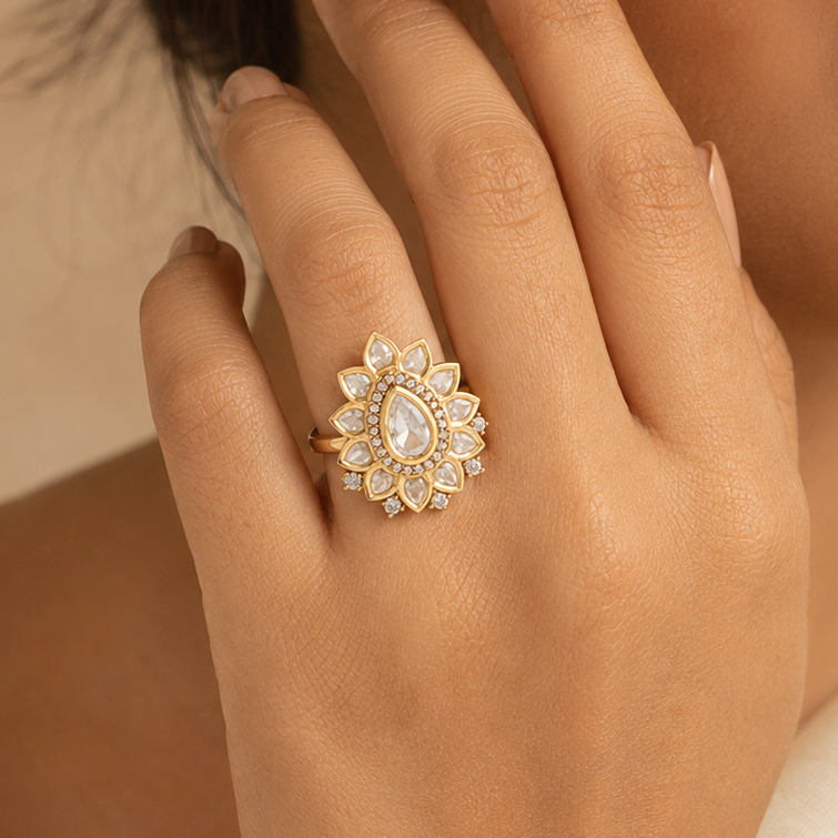 Woman wearing a gold-finish floral finger ring with clear diamond-look stones
