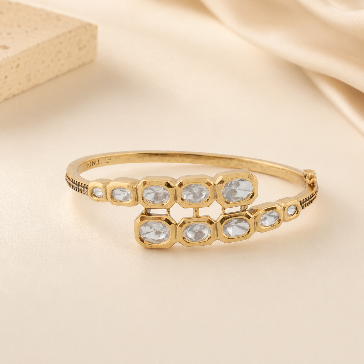 Vihana gold Polki cascade bracelet displayed in a warm champagne luxury setting